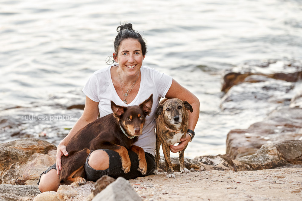 female owner with two dogs sitting beside water