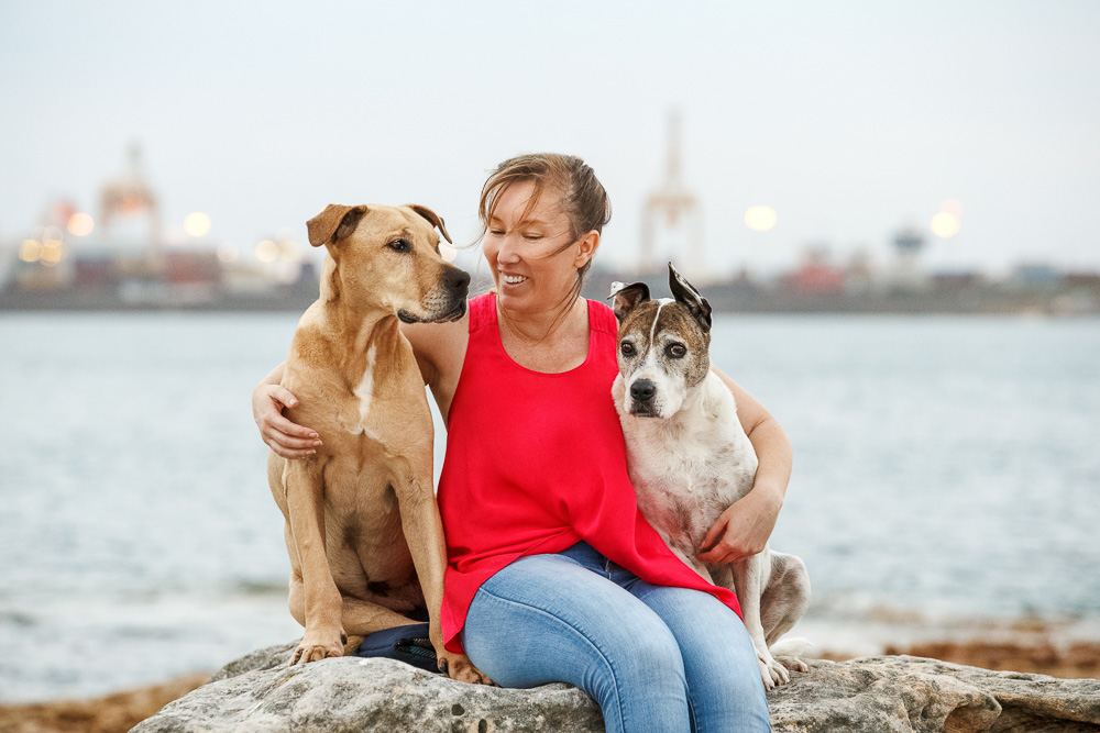female hugging her two dogs and smiling