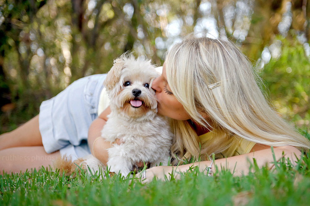 pretty blonde girl kissing her small white dog